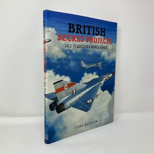 Puede incluir: Un libro titulado "British Secret Projects: Jet Fighters Since 1950" de Tony Butler. La portada presenta un avión de combate azul y plateado contra un cielo azul con nubes blancas.