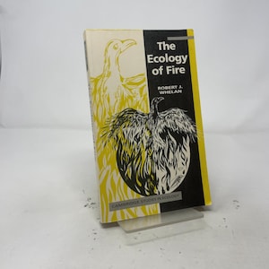 May include: A softcover book titled The Ecology of Fire by Robert J. Whelan. The cover features a black and white illustration of a bird rising from flames against a yellow background, with the text Cambridge Studies in Ecology at the base.