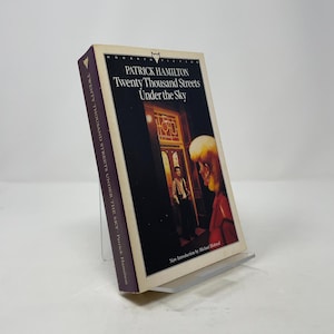 May include: A white ceramic mug with a black handle and the text "But First, Coffee" in a bold, black font. The mug is set against a blurred background, suggesting a cozy setting.