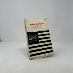 May include: A hardcover book titled "Empire and Nation" with a black and white striped design on the cover. The book also features the text "Join or Die" and the names of the authors. The book is displayed on a clear stand.