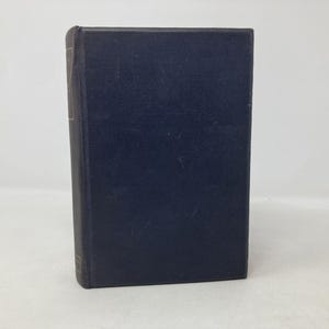 Peut inclure: Un livre à couverture rigide bleu foncé, debout. La couverture a un aspect légèrement texturé. Le dos est visible, et les bords des pages sont visibles. Le livre semble en bon état.