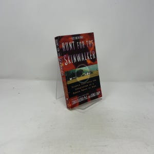 May include: A hardcover book titled "Hunt for the Skinwalker" with a red and orange cover. The book's title is in large white letters. The cover features a landscape image and the text "Science Confronts the Unexplained at a Remote Ranch in Utah."