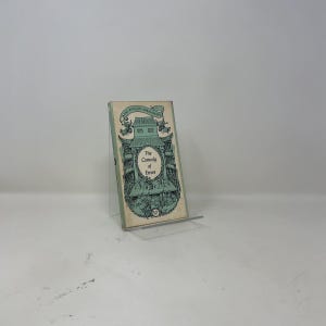 May include: A paperback book titled The Pelican Shakespeare The Comedy of Errors with a light green cover featuring a detailed black line illustration of a theater stage and architectural elements, displayed on a clear acrylic stand.