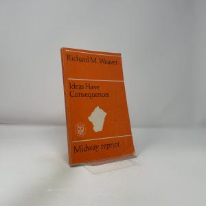 Puede incluir: Un libro naranja titulado "Ideas Have Consequences" de Richard M. Weaver. El libro es una reimpresión de Midway. La portada presenta texto blanco y un gráfico blanco. El libro está apoyado en un soporte transparente.