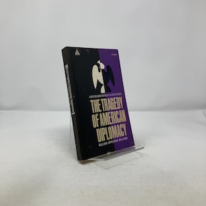 May include: A hardcover book titled "The Tragedy of American Diplomacy" by William Appleman Williams. The book has a black and purple cover with a graphic design and the price $1.05.