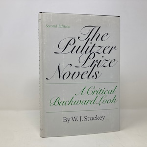 May include: A white book with the title "The Pulitzer Prize Novels: A Critical Backward Look" by W. J. Stuckey. The book is a second edition.