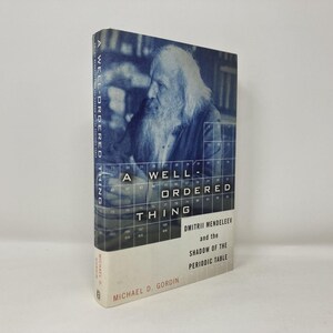 May include: A hardcover book titled "A Well-Ordered Thing" by Michael D. Gordin. The cover features a blue-toned image of a man with a long beard and the title in bold white letters. The book explores Dmitri Mendeleev and the Periodic Table.