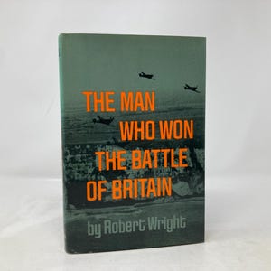 May include: A green book cover with the title "The Man Who Won The Battle Of Britain" in orange text. The author, "Robert Wright", is also in orange text. The cover features a black and white image of airplanes flying over a coastline.