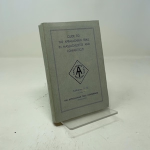 May include: A gray softcover book titled Guide to the Appalachian Trail in Massachusetts and Connecticut, Publication No. 21, by The Appalachian Trail Conference. The cover features a black diamond-shaped logo with the letters AT inside.