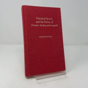 May include: A red hardcover book titled Classical Greece and the Poetry of Chenier, Shelley, and Leopardi by Stephen Rogers. The front cover features gold text centered on the solid red fabric-textured surface of the book's exterior binding.