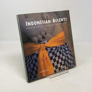 Peut inclure: Livre intitulé "Indonesian Accents" avec le sous-titre "Architecture Interior Design Art". La couverture présente une statue avec une écharpe orange et un tissu à carreaux. Le nom de l'auteur, Tan Hock Beng, est visible.