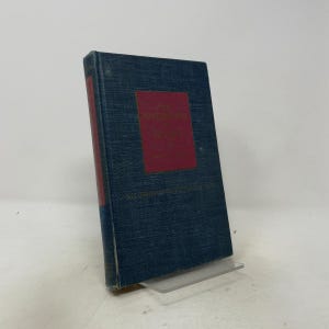 May include: A hardcover book with a textured dark blue fabric cover and a rectangular red label on the front. The red label features gold embossed text that reads The Masterpieces of Painting. The book spine is also red with gold lettering.