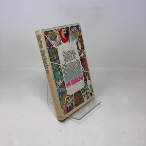 Könnte beinhalten: Ein Vintage-Buch mit dem Titel "Astro-Analysis" von Ilya Chamberlin. Das Cover zeigt farbenfrohe Illustrationen und den Titel in einer stilisierten Schriftart. Das Buch wird auf einem transparenten Acrylständer präsentiert.