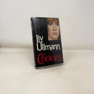 以下が含まれることがあります： リヴ・ウルマン著の「Choices」というタイトルのハードカバー本。表紙には赤毛の女性の肖像画と著者の名前が白で描かれています。タイトルは黒い背景に赤色で表示されています。