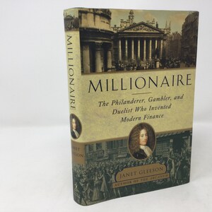May include: A book cover with a tan background and the title "MILLIONAIRE" in large, bold, black letters. The subtitle is "The Philanderer, Gambler, and Duelist Who Invented Modern Finance". The cover also features a portrait of a man in a white wig and a black and white building in the background.