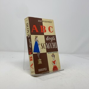 May include: A brown book with the title "ABC degli Scacchi" by Ugo Pasquinelli. The book cover features a chessboard with a queen and a king, and the text "Decima Edizione" is printed below the chessboard.