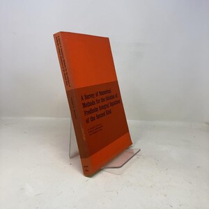 Peut inclure: Un livre orange intitulé "A Survey of Numerical Methods for the Solution of Fredholm Integral Equations of the Second Kind". Le livre est posé sur un présentoir en plastique transparent. La tranche du livre porte le titre imprimé verticalement.