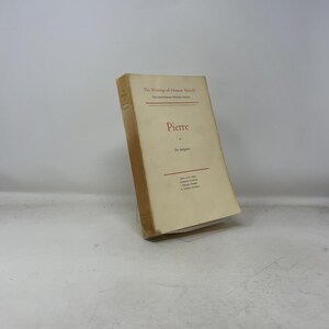 May include: A vintage book titled "Pierre" by Herman Melville. The cover is a light beige color with red text. The book is slightly angled, showcasing its aged appearance and the title prominently displayed.