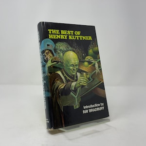 Op de afbeelding: Een vintage paperback boek getiteld "THE BEST OF HENRY KUTTNER" met een illustratie van een groenhuidige alien die een glas vasthoudt. De cover bevat andere figuren en de tekst "introduction by RAY BRADBURY".