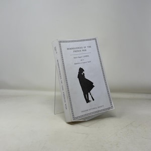 May include: A white book titled "Reminiscences of the French War" with black text and a silhouette illustration. The book is propped up on a clear stand. The cover also includes the text "Robert Rogers' Journal and a Memoir of General Stark" and "Freedom Historical Society."