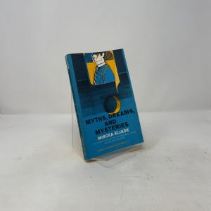 May include: A paperback book titled Myths, Dreams, and Mysteries by Mircea Eliade. The cover features a blue background with a stylized illustration of a person in a blue suit and a yellow crescent moon. The text is printed in black and white.