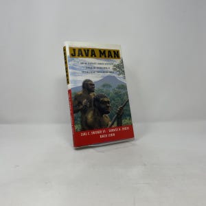 Könnte beinhalten: Ein gebundenes Buch mit dem Titel Java Man von Carl C. Swisher III, Garniss H. Curtis und Roger Lewin. Das Cover zeigt eine Illustration von zwei Hominiden in einer Dschungellandschaft mit einem Berg im Hintergrund, eingerahmt in Rot und Weiß.