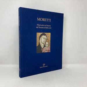 May include: A blue hardcover book titled "Moretti: Pittori attivi in Toscana dal Trecento al Settecento" with a gold title and a painting of a woman and child on the cover.