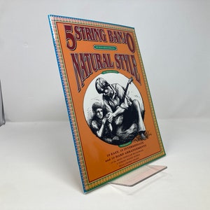 May include: A book titled "5 String Banjo Natural Style" with a drawing of two people playing a banjo. The book includes 10 easy, 10 intermediate, and 10 hard arrangements of popular banjo tunes.