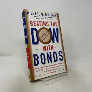 May include: A hardcover book titled Beating the Dow with Bonds by Michael B. O'Higgins. The cover features a white background with blue and red text, a brown circular graphic containing a line chart, and a red vertical stripe on the spine.