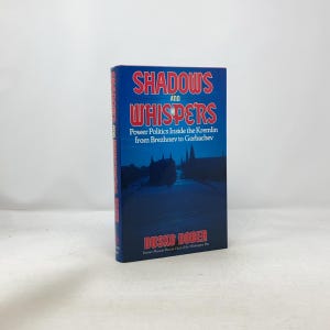 May include: A hardcover book titled "Shadows and Whispers" with a blue cover. The title is in red and white, with the subtitle "Power Politics Inside the Kremlin from Brezhnev to Gorbachev." The author's name is Dusko Doder.