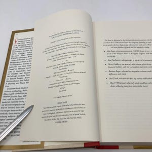 Pode incluir: Livro aberto com texto nas páginas. A página esquerda tem uma lista de nomes, a página direita tem uma dedicatória. Uma caneta prateada repousa na página esquerda. O livro é intitulado "Booknotes: Life Stories of Notable Biographers on the People Who Shaped America" por Brian Lamb.