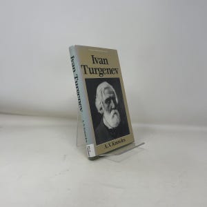 Puede incluir: Un libro de tapa dura titulado "Ivan Turguénev" de A. V. Knowles. El libro presenta un retrato en blanco y negro de un hombre con una larga barba blanca. El libro está apoyado en un soporte de plástico transparente.
