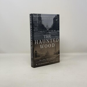 Puede incluir: Un libro de tapa dura titulado "The Haunted Wood: Soviet Espionage in America, The Stalin Era" de Allen Weinstein y Alexander Vassiliev. La portada presenta una fotografía en blanco y negro de una calle en Washington D.C. con el Capitolio en el fondo.