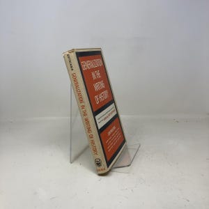 May include: A vintage book titled "Generalization in the Writing of History" by Louis Gottschalk. The book has a white cover with red and black text. The book is displayed on a clear acrylic stand.