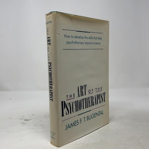 May include: A hardcover book titled The Art of the Psychotherapist by James F. T. Bugental. The off-white dust jacket features dark blue and black text, with the subtitle How to develop the skills that take psychotherapy beyond science.