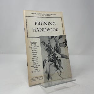 May include: A vintage "Pruning Handbook" book from the Brooklyn Botanic Garden Record. The cover features the title and a black and white illustration of pruning shears and leaves. The book's contents include methods for pruning trees, shrubs, and various plant types.
