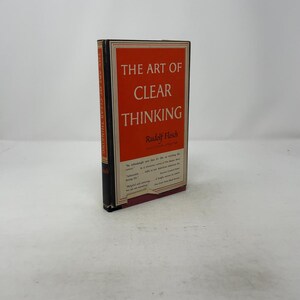 Könnte beinhalten: Ein Hardcover-Buch mit dem Titel "The Art of Clear Thinking" von Rudolf Flesch. Das Buch hat einen rot-weißen Einband mit schwarzem Text. Der Buchrücken ist schwarz mit weißem Text. Das Buch liegt auf einer weißen Oberfläche.