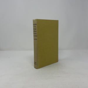 May include: A hardcover book with a light yellow cover. The book's spine displays the title "Higgins & the British Colonial System 1660-1960" and the author's name. The book is standing upright on a white surface.