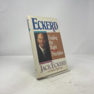 Puede incluir: Un libro de tapa dura titulado "ECKERD" con el subtítulo "Finding the Right Prescription" de Jack Eckerd y Charles Paul Conn. La portada presenta un retrato de un hombre con traje y corbata.