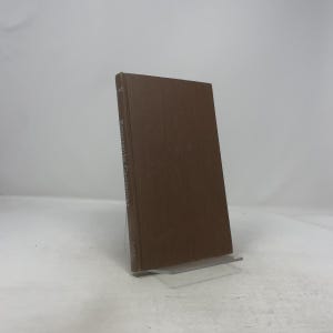 May include: A brown hardcover book titled "Panorama Grammar" is displayed upright on a clear stand. The book's spine is visible, with the title printed vertically in white. The background is plain white.