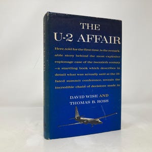 May include: A blue book cover with the title "THE U-2 AFFAIR" in white text. The book cover also features a black and white image of a U-2 spy plane in flight. The authors' names, "DAVID WISE AND THOMAS B. ROSS", are printed in white text below the image.