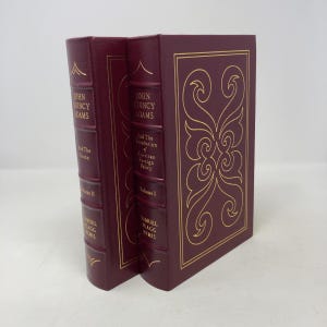Puede incluir: Dos libros de color burdeos con letras doradas y detalles decorativos. Las lomos dicen "John Quincy Adams" y "And The Union, Volume II" y "Samuel Flagg Bemis". El otro libro dice "John Quincy Adams" y "And The Foundation of American Foreign Policy, Volume I."