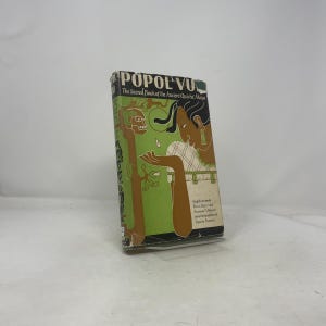 May include: A hardcover book titled "Popol Vuh: The Sacred Book of the Ancient Quiché Maya." The cover features a green background with an illustration of a woman and a stylized figure. The book's spine is visible, showing the title.