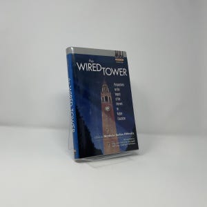 May include: A hardcover book titled "The Wired Tower" with a blue and white cover. The cover features a nighttime image of a tall clock tower. The book's spine also displays the title. The book is about the impact of the internet on higher education.