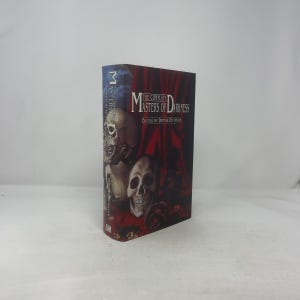 Puede incluir: Un libro de tapa dura titulado "The Complete Masters of Darkness" con una portada que presenta calaveras e imágenes en rojo oscuro y negro. El lomo muestra el título y el nombre del autor. El libro está de pie.