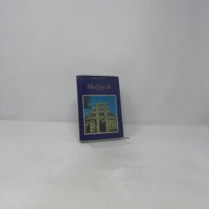 Puede incluir: Un libro azul titulado "Monuments of the World" se muestra en un soporte acrílico transparente. La portada presenta una imagen en color de una estructura histórica. El libro forma parte de la "Heritage Series".