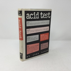 Puede incluir: Una portada de libro en blanco y negro con el título "acid test" en letras blancas grandes. El libro es de John Simon y presenta un diseño rojo y negro con texto sobre el contenido del libro.