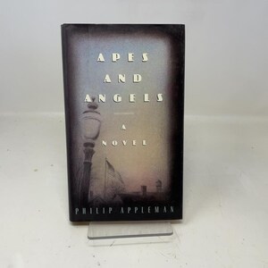 May include: A novel titled "Apes and Angels" by Philip Appleman. The book cover features a dark, atmospheric design with the title in white capital letters. A silhouette of a lamppost and a flag are visible.