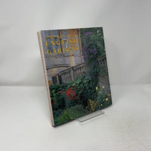 May include: A hardcover book titled One Hundred English Gardens by Patrick Taylor. The cover features a photograph of a stone building facade partially covered in climbing purple flowers, green foliage, and red and yellow blossoms in a garden.
