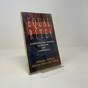May include: A softcover book titled Equal Rites: Lesbian and Gay Worship, Ceremonies, and Celebrations, edited by Kittredge Cherry and Zalmon Sherwood. The cover features a dark, pixelated background with a large red rectangle and yellow text.
